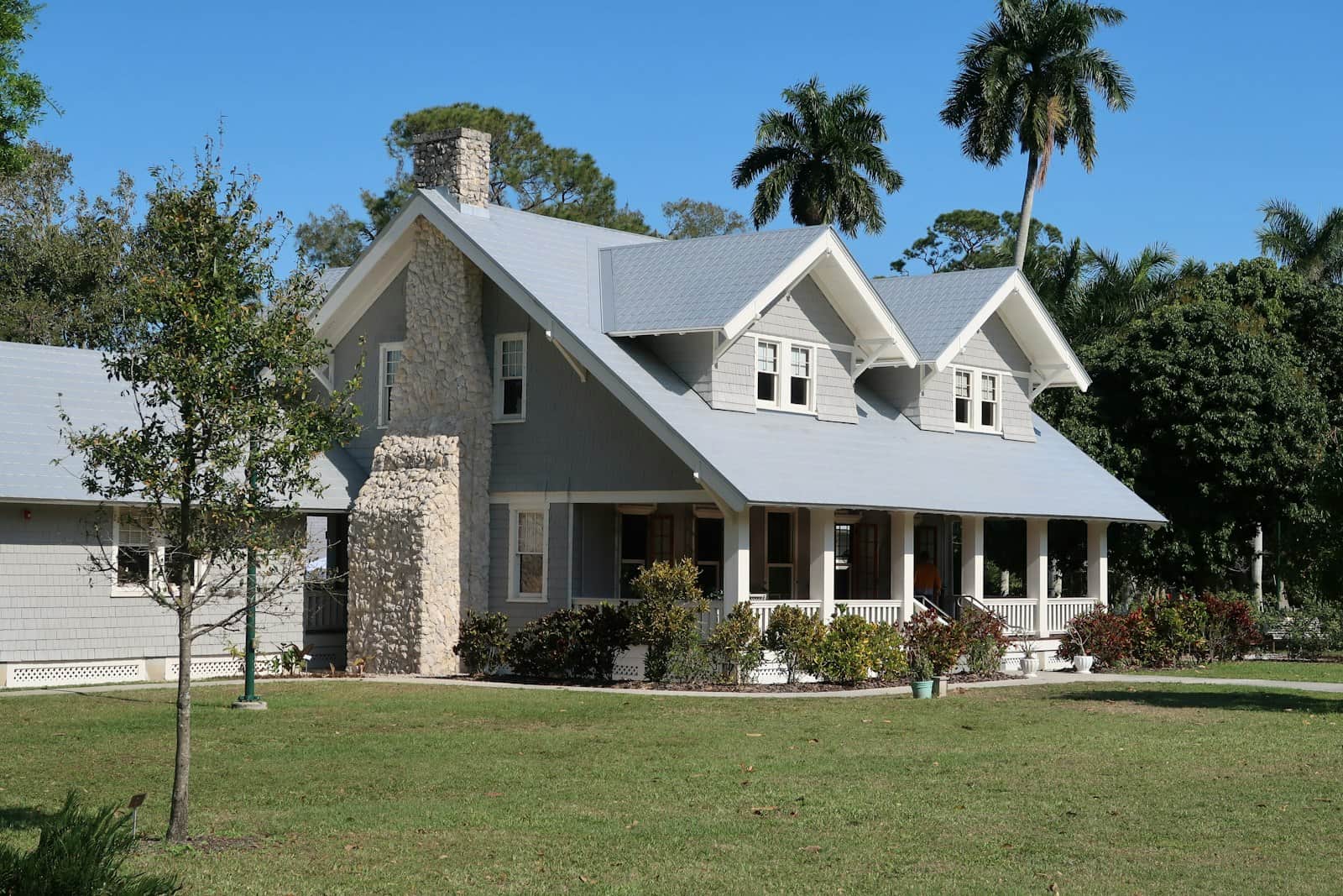 Craftsman home with a deep porch under royal palms and a bright Florida sky